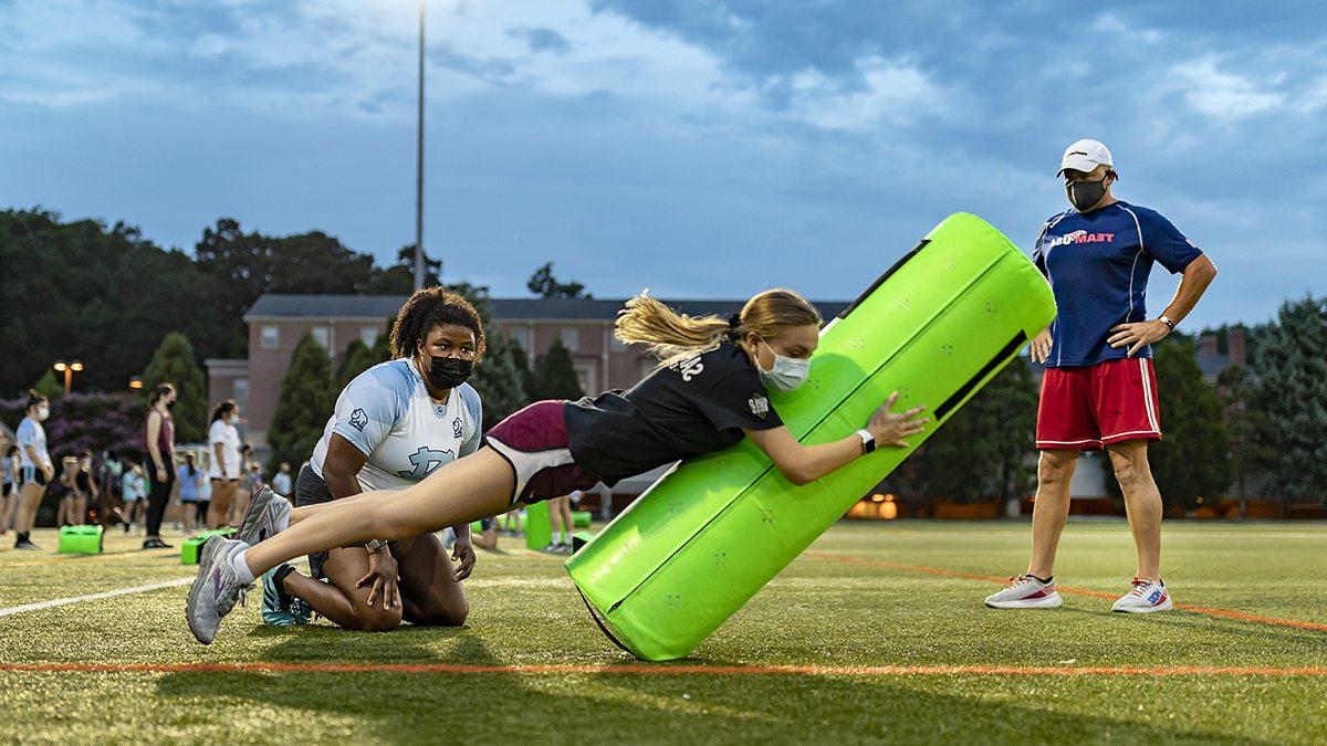 A rugby player tackles a large pad.