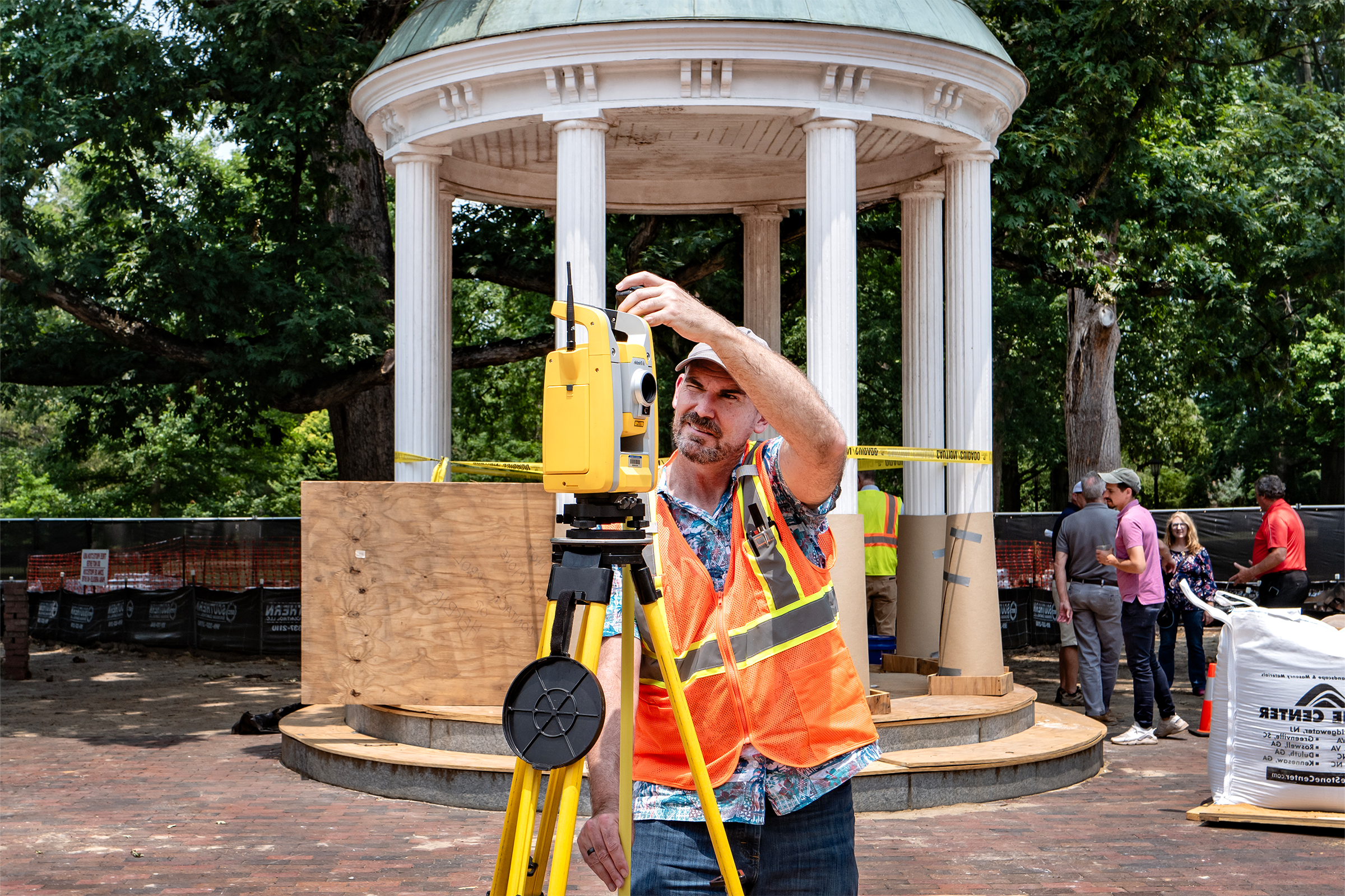 A worker using surveying equipment next to a well.