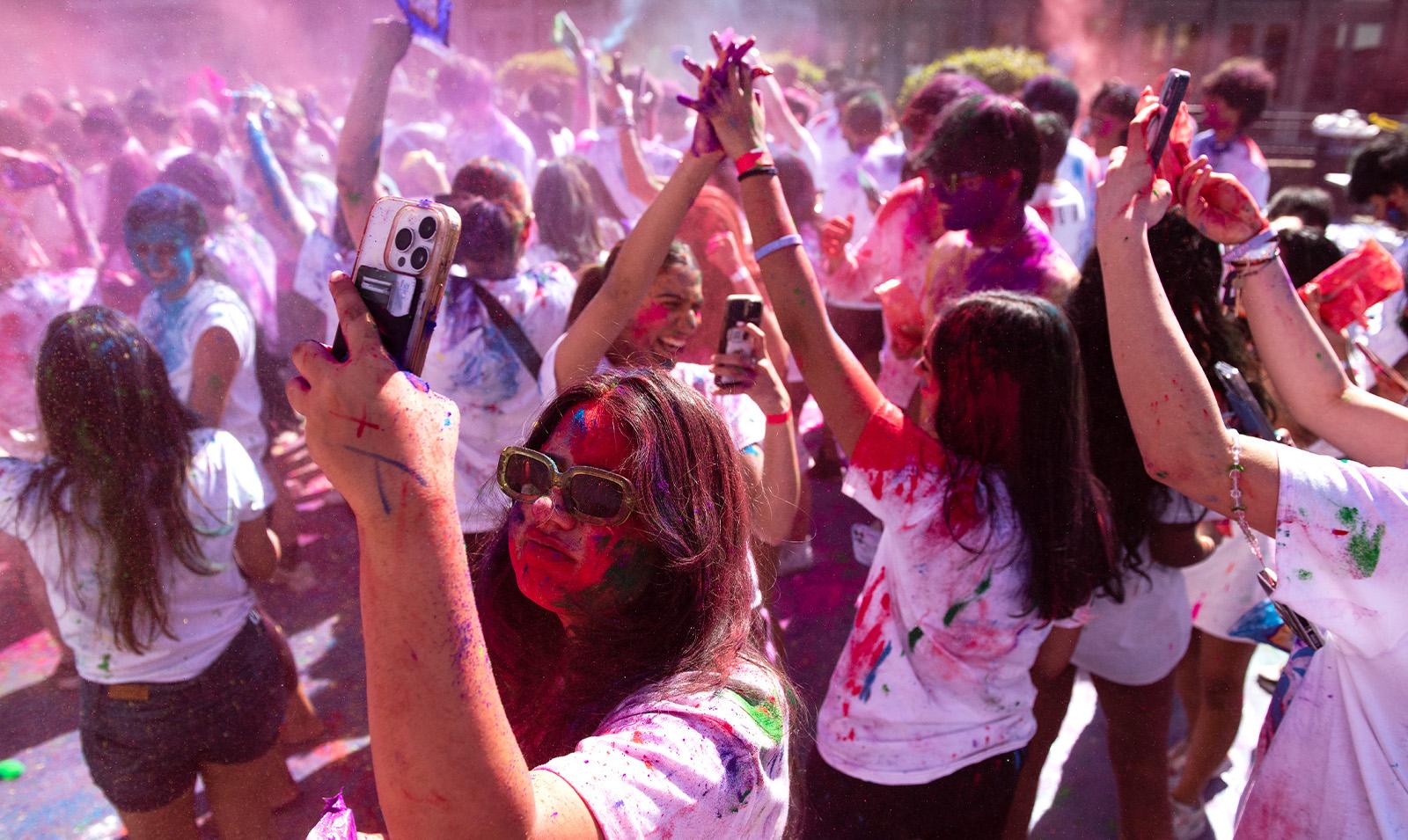 Crowd of students covered in paint celebrating Holi.