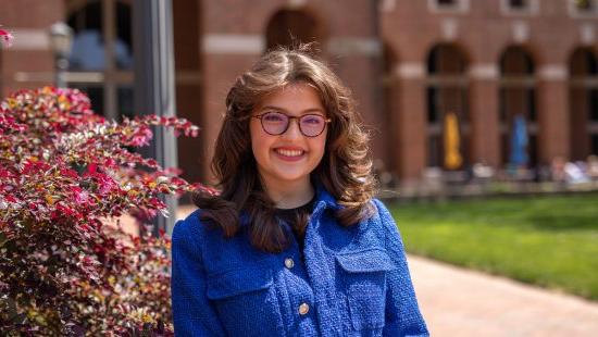 Sasha Surkin in blue jacket posing on UNC campus.