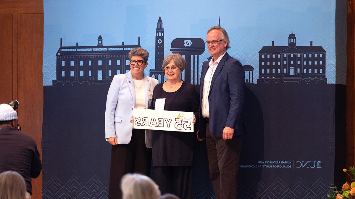 Two human resources office leaders posing for a photo with a UNC-Chapel Hill employee being honored for 55 years of state employment.